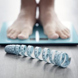 Feet on bathroom scale with measuring tape